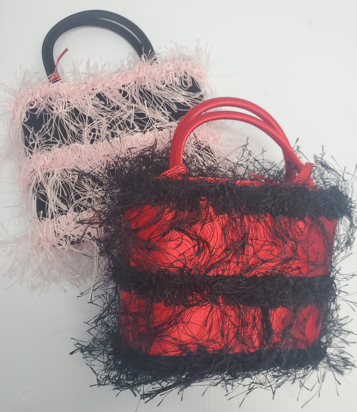 satin evening bags with 3 equally divided rows of colorful and feathery hair like trim. black with baby pink or red with black
