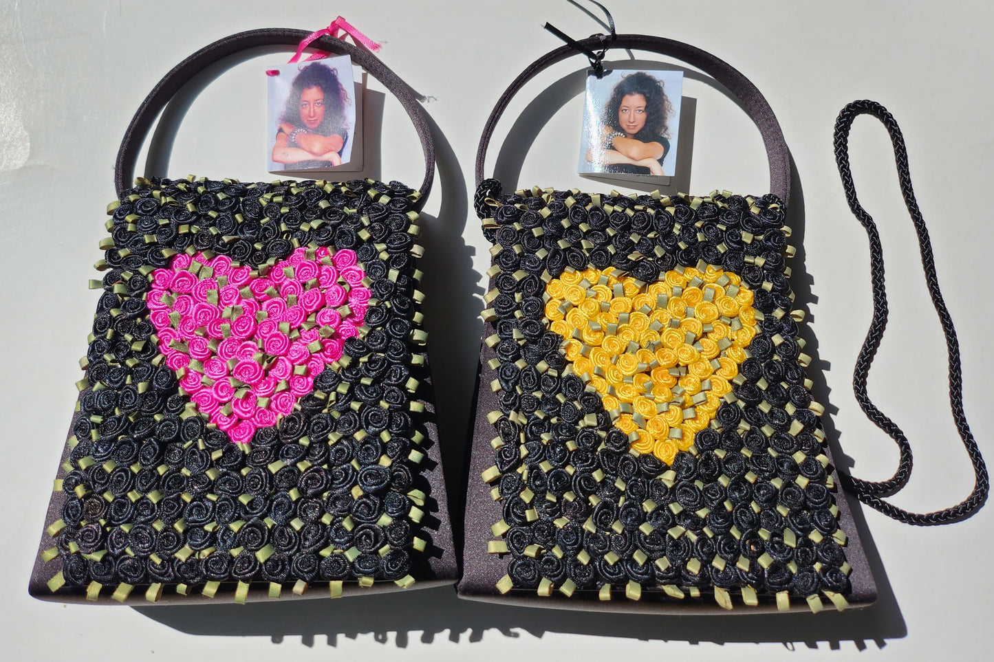 black satin evening purses covered in black silk ribbon roses with the choice of a fuscia heart design made of roses or a center heart design of yellow roses
