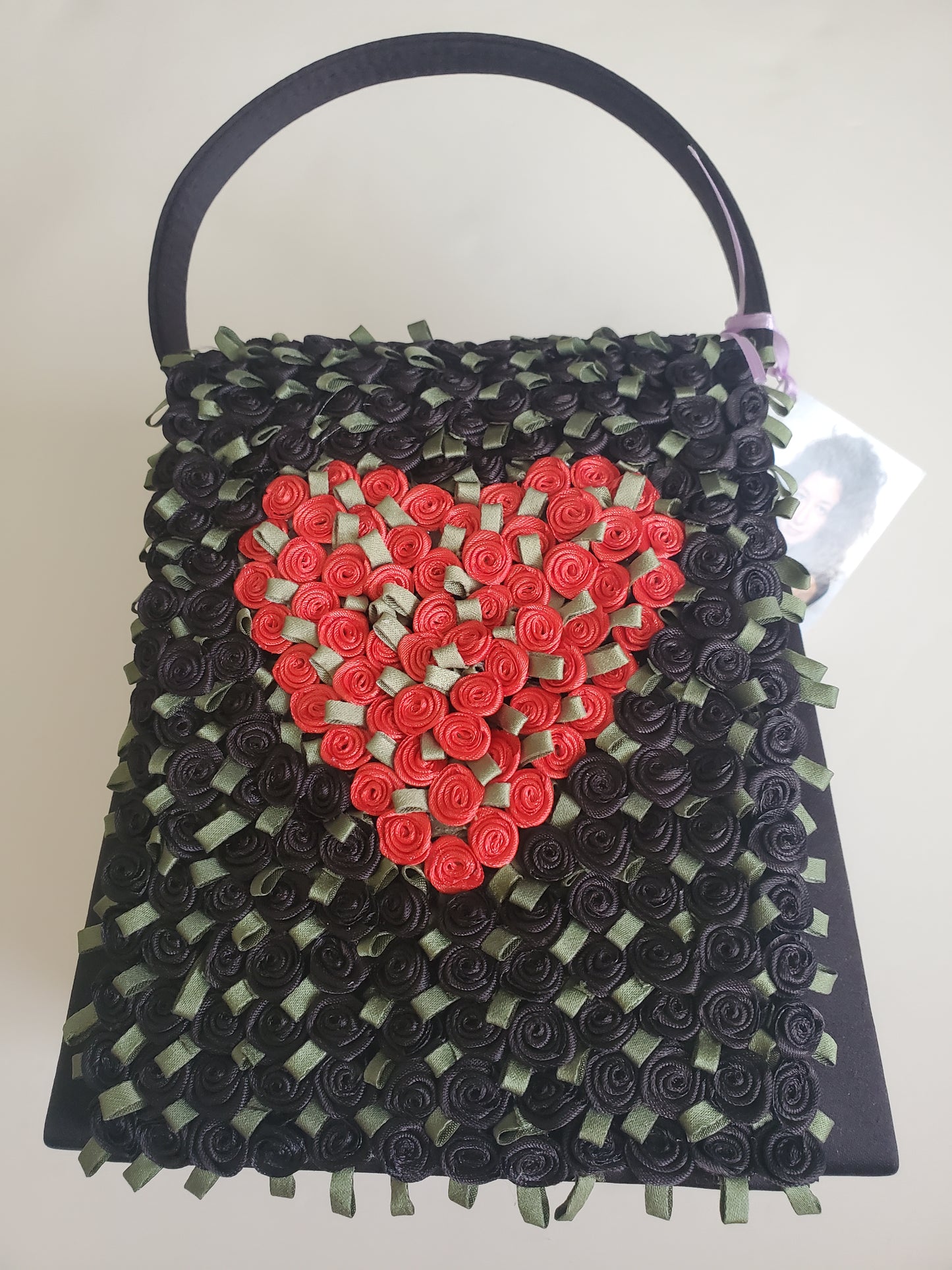 Black evening purse covered in black silk ribbon roses  with a center heart design in red ribbon roses